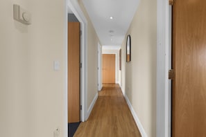 Ein Korridor mit Holzboden, weißen Wänden und Türen an beiden Seiten.