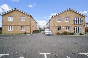 A residential street with two brick houses, a car parked in the middle, and a clear sky. - Heathrow Living Apt. 08 by 360 Stays (Stanwell)