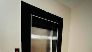 A closed elevator in a hallway with a control panel on the wall. - Fabulous 1-bedroom apartment (Nairobi)