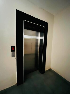 A closed elevator in a hallway with a control panel on the wall. - Fabulous 1-bedroom apartment (Nairobi)