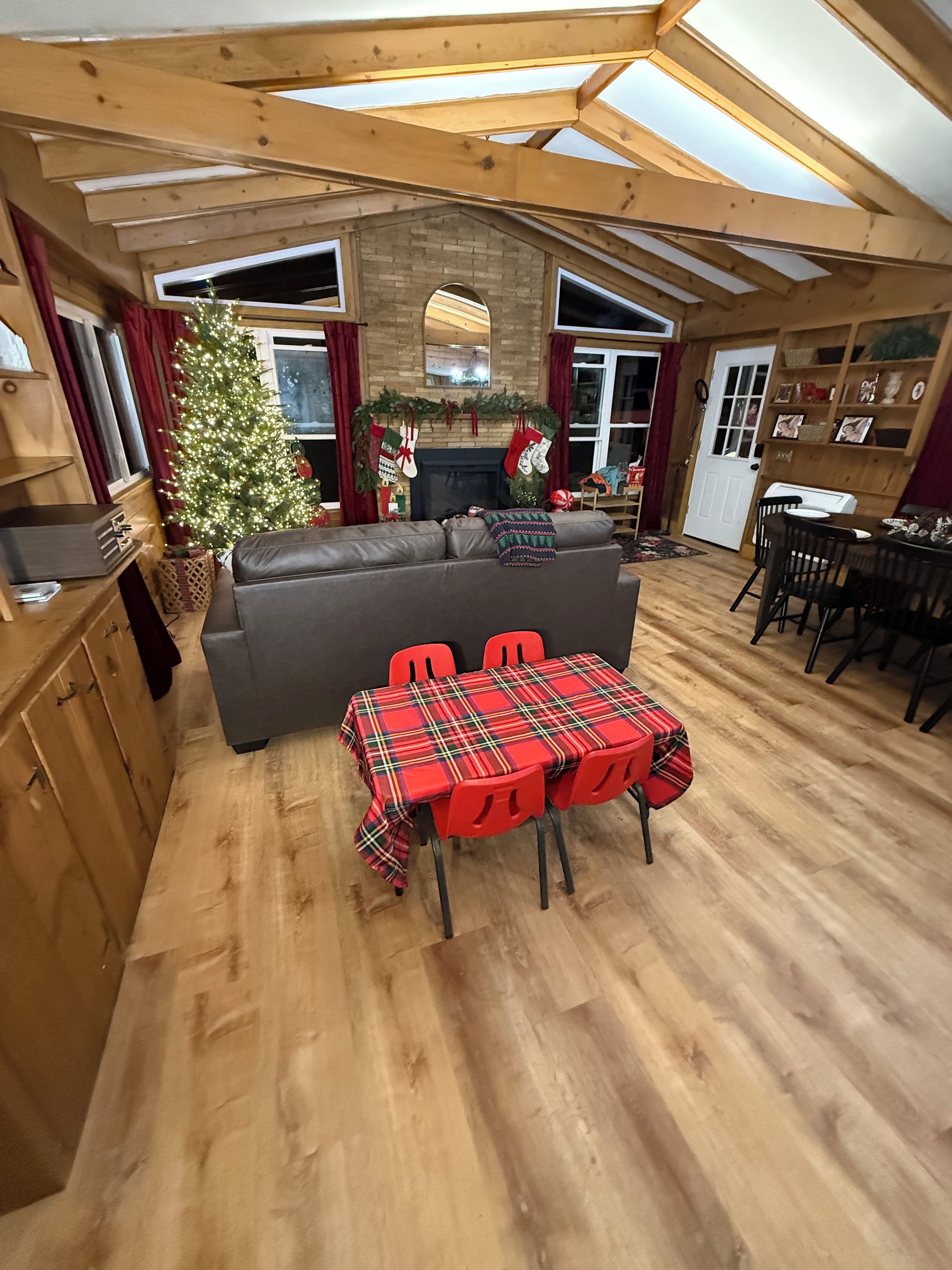 A cozy interior with a dining area, a fireplace, and a Christmas tree.