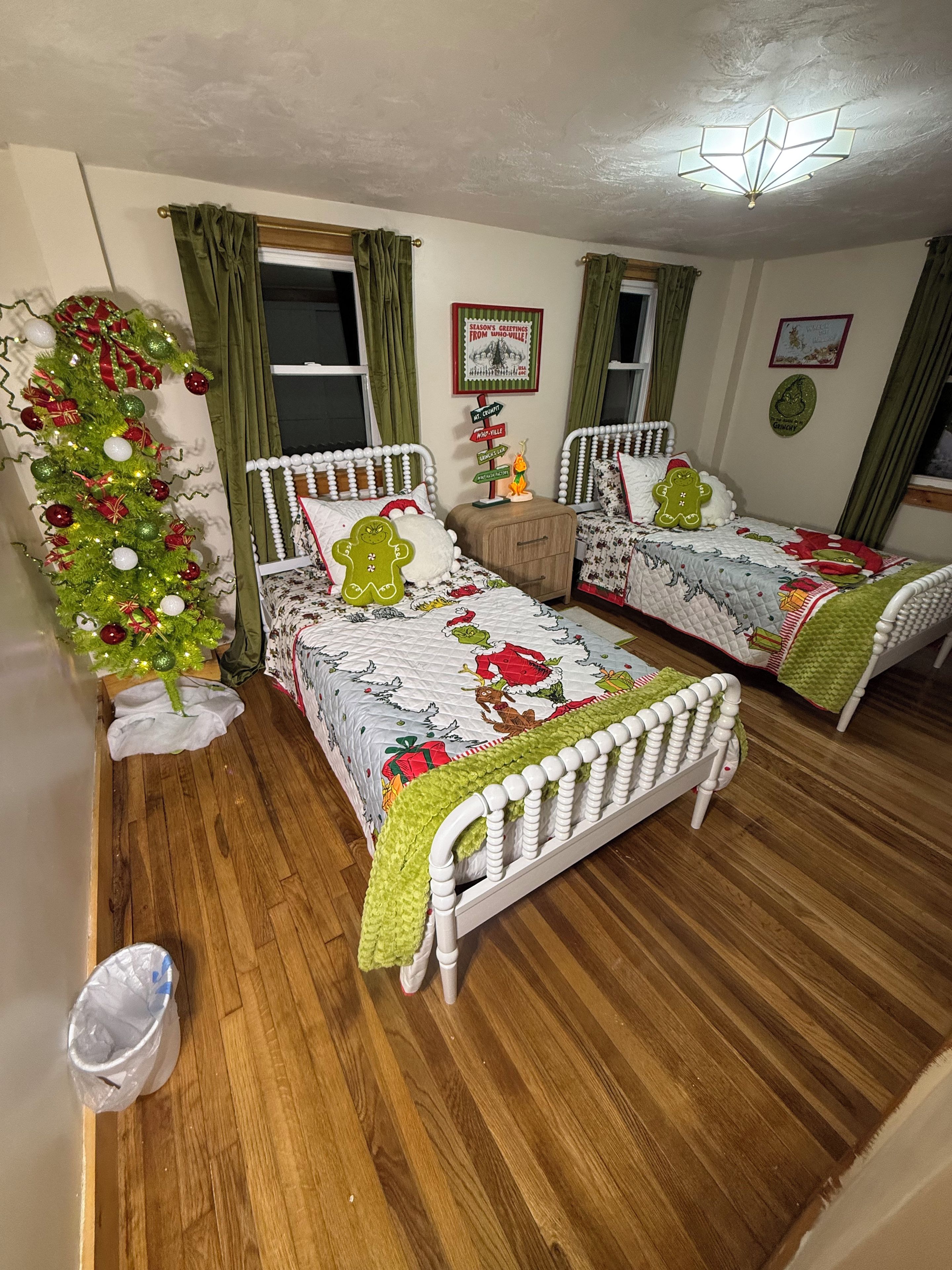 A room with two single beds, a Christmas tree, and a wall sign.