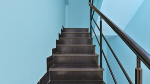 A staircase with a handrail and a light blue wall. - Dev Hotel Mansarovar (Jaipur)