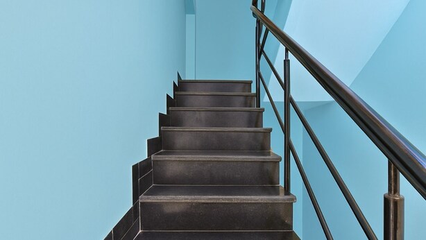 A staircase with a handrail and a light blue wall. - Dev Hotel Mansarovar (Jaipur)