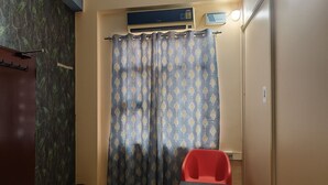 A bathroom with a shower curtain, a red chair, and an air conditioning unit. - Dev Hotel Mansarovar (Jaipur)