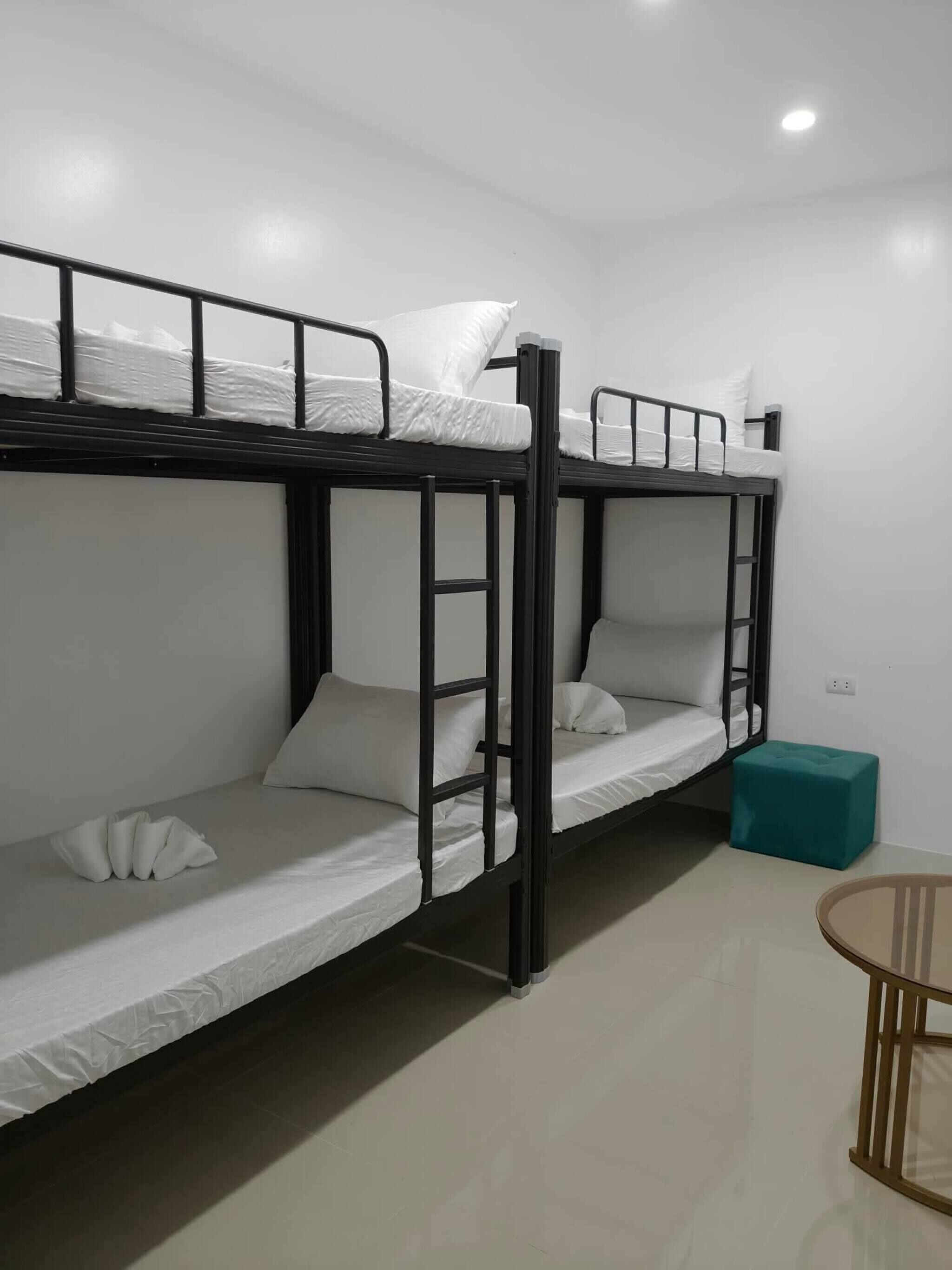 A bunk bed room with a small table and a stool.