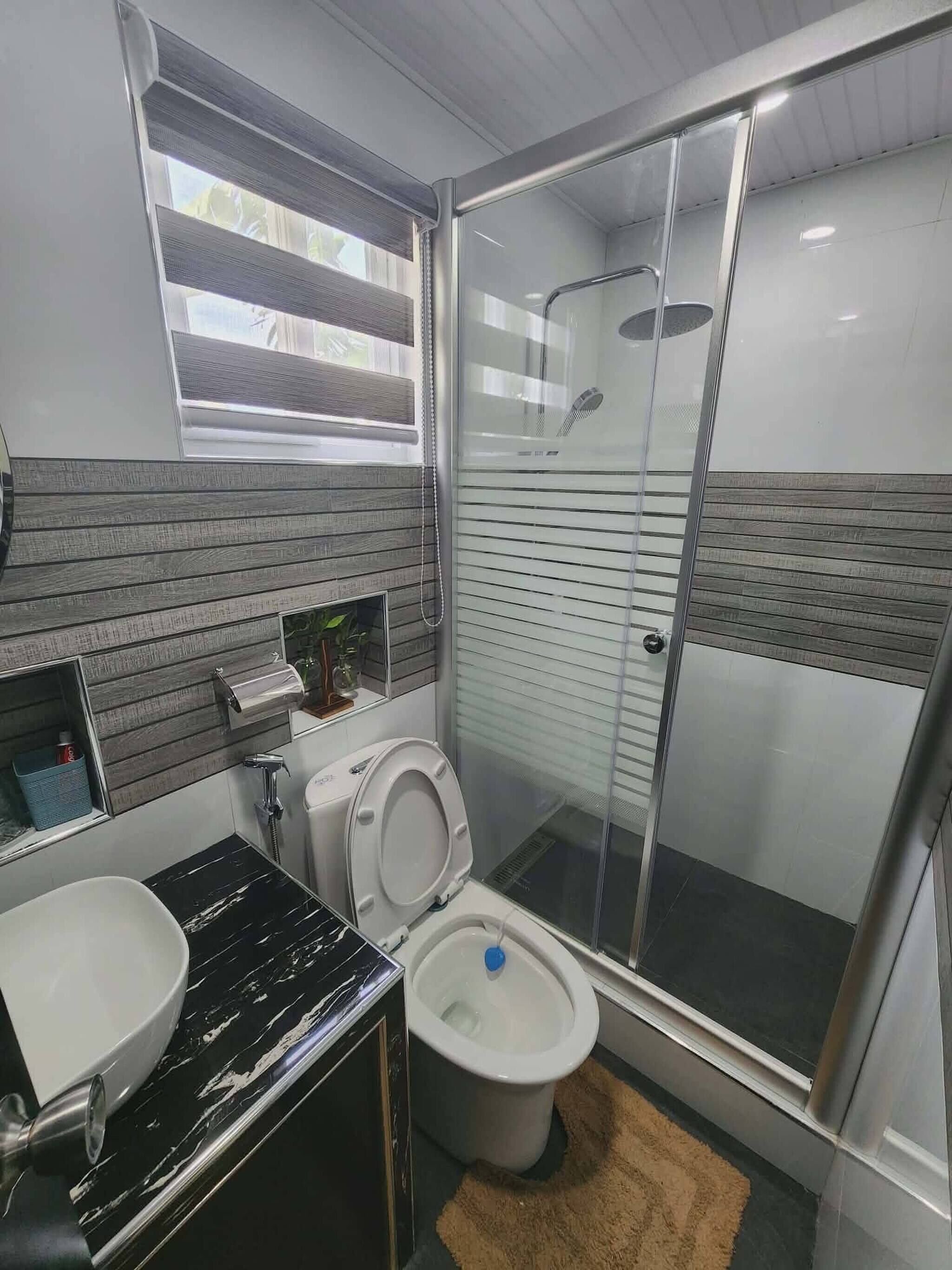 Un baño moderno con inodoro, lavamanos y zona de ducha.