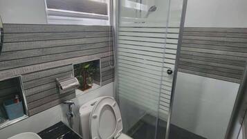 Un baño moderno con inodoro, lavamanos y zona de ducha.