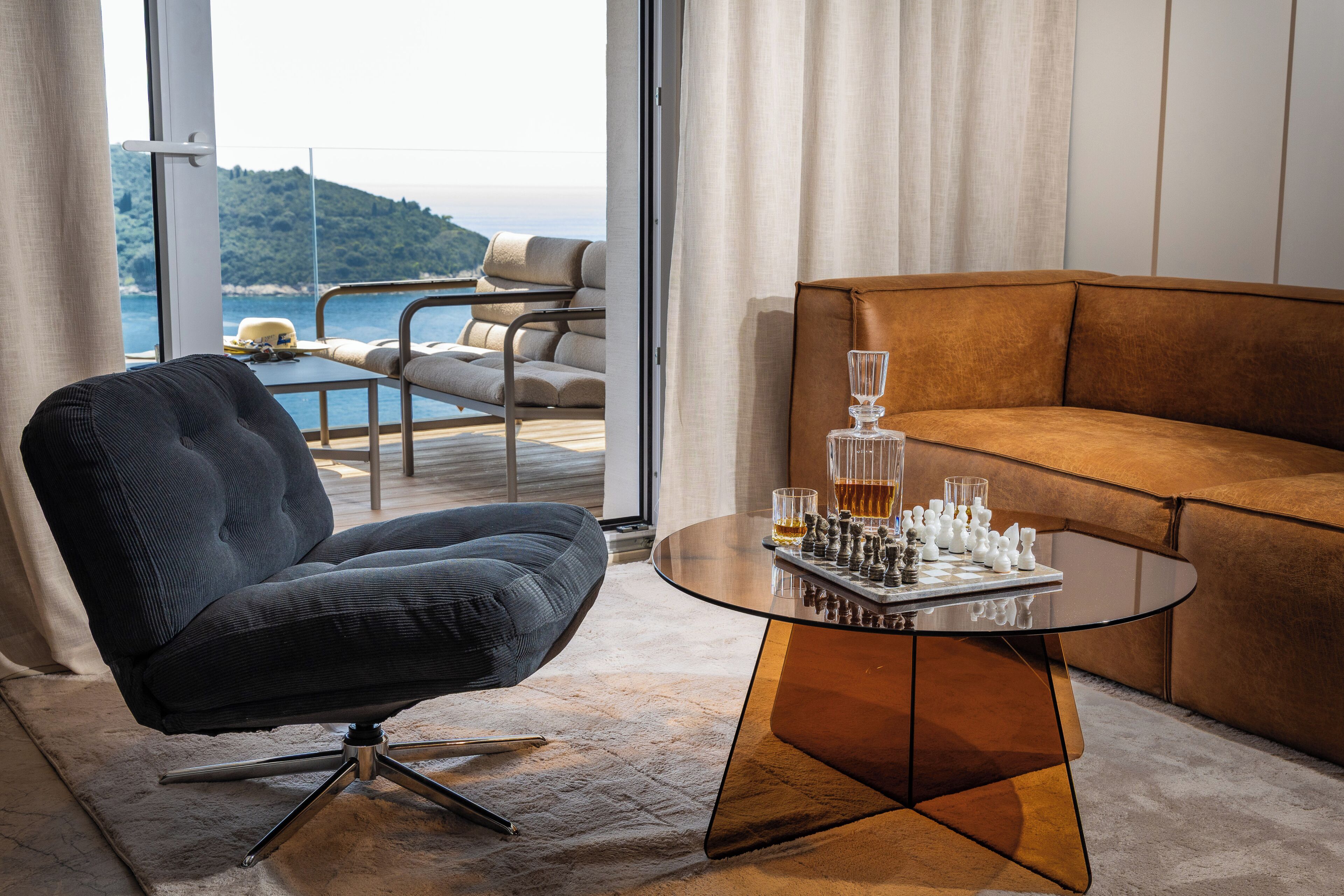 Uma sala de estar moderna com um sofá, uma poltrona e uma mesa com peças de xadrez e copos.