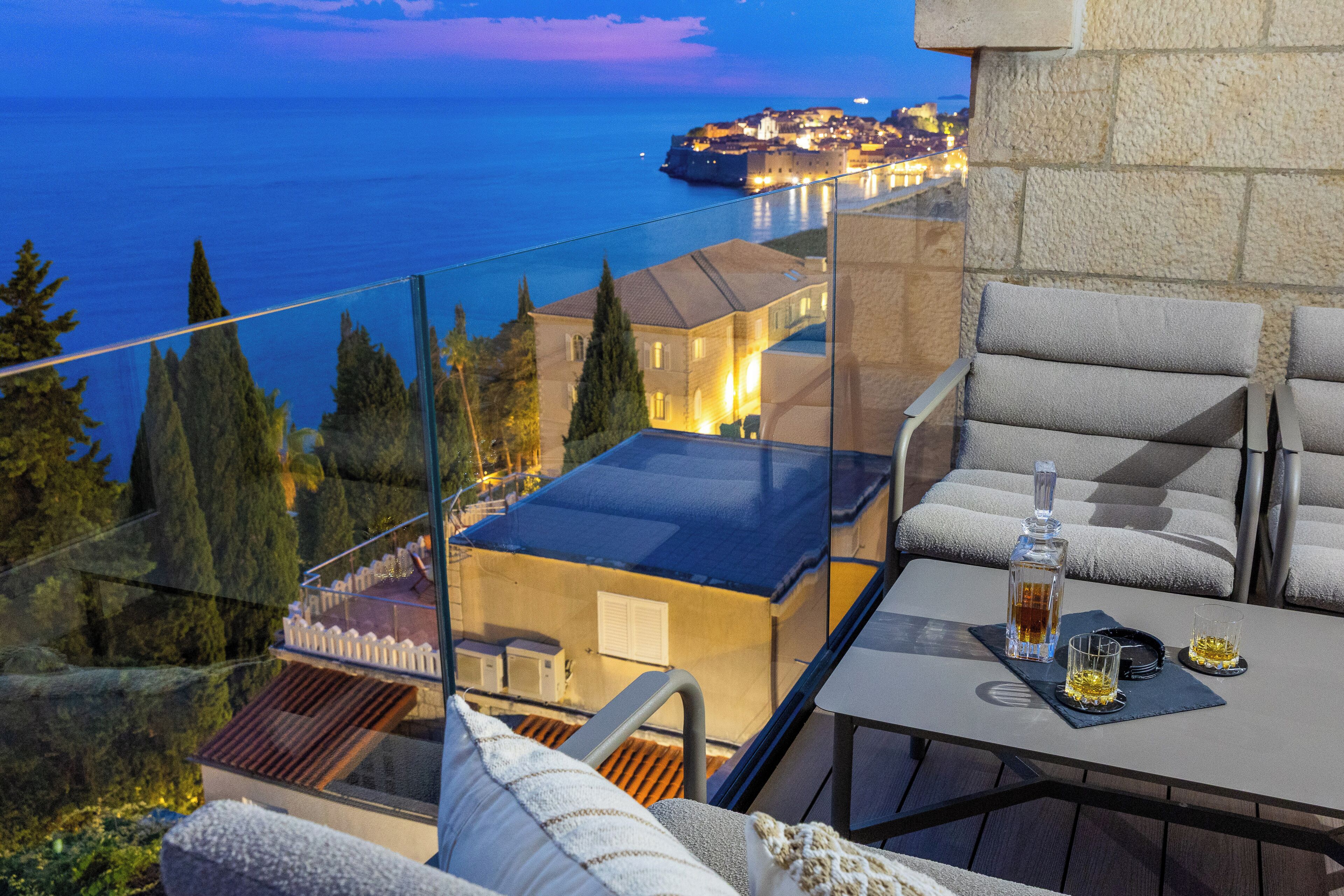 Ein Balkon mit Tisch, Stühlen und einer Flasche Alkohol.