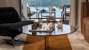Ett modernt vardagsrum med ett soffbord i glas, ett schackspel och utsikt över havet.