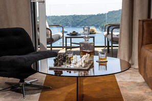 Ein modernes Wohnzimmer mit einem Glastisch, einem Schachspiel und Blick auf das Meer.