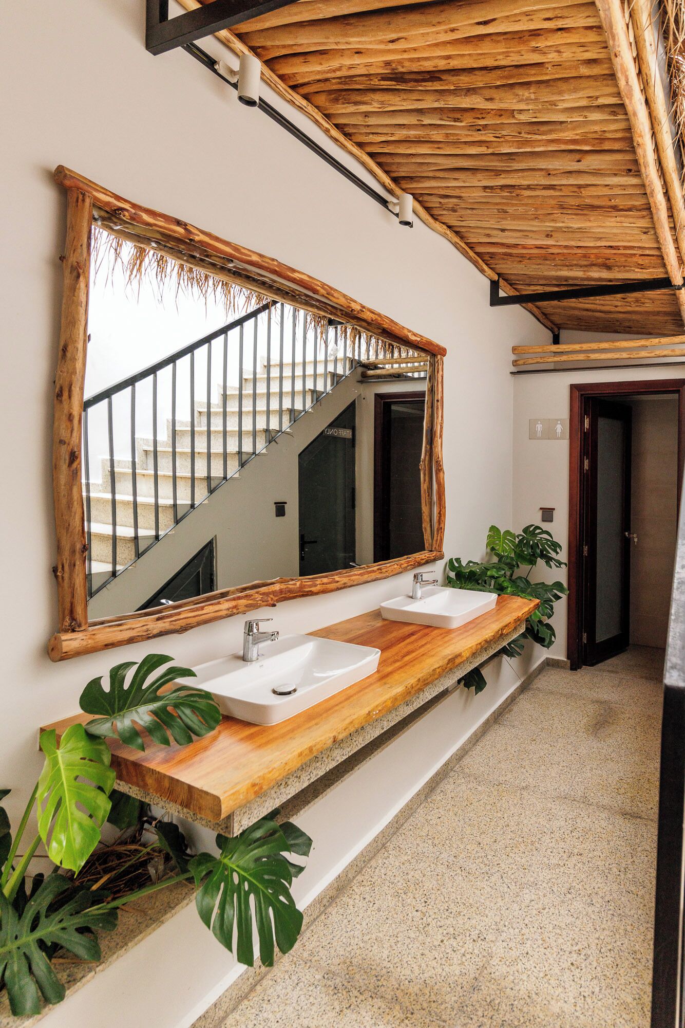 Ein Badezimmer mit einem Holzbadezimmer-Möbel, zwei Waschbecken, einem großen Spiegel und einer Treppe, die in ein Obergeschoss führt.