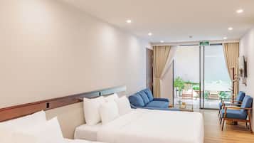 Habitación de hotel con dos camas, un balcón con asientos y vistas al exterior.