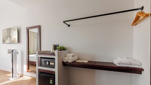 A hotel room with a built-in mini-fridge, a coffee maker, a towel rack, and a pair of slippers on the floor.