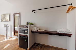 A hotel room with a built-in mini-fridge, a coffee maker, a towel rack, and a pair of slippers on the floor.