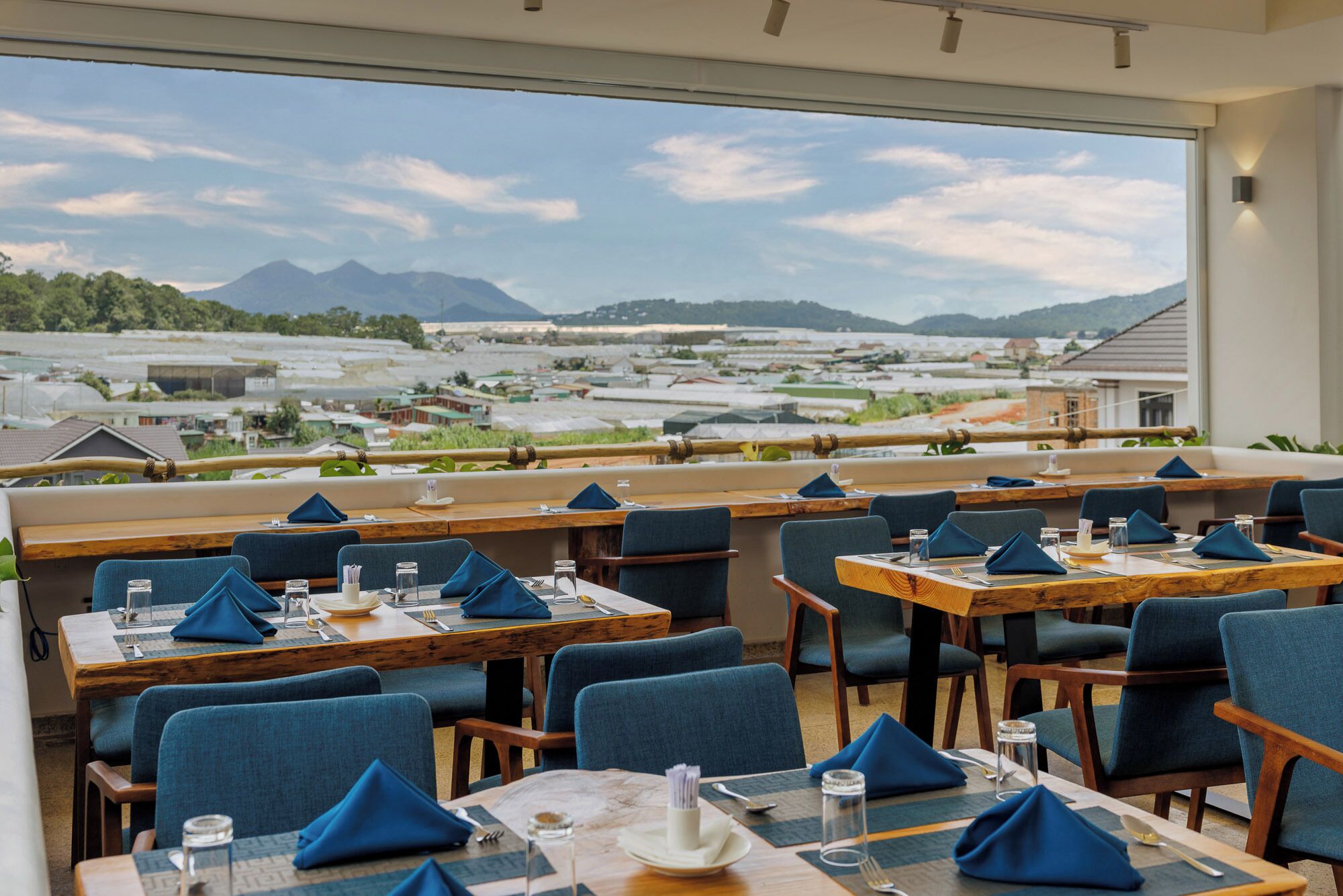 A restaurant with tables set for dining, a view of a mountainous landscape, and a modern interior design.