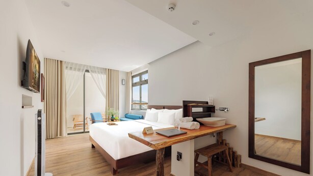 A hotel room with a bed, desk, and a large mirror.