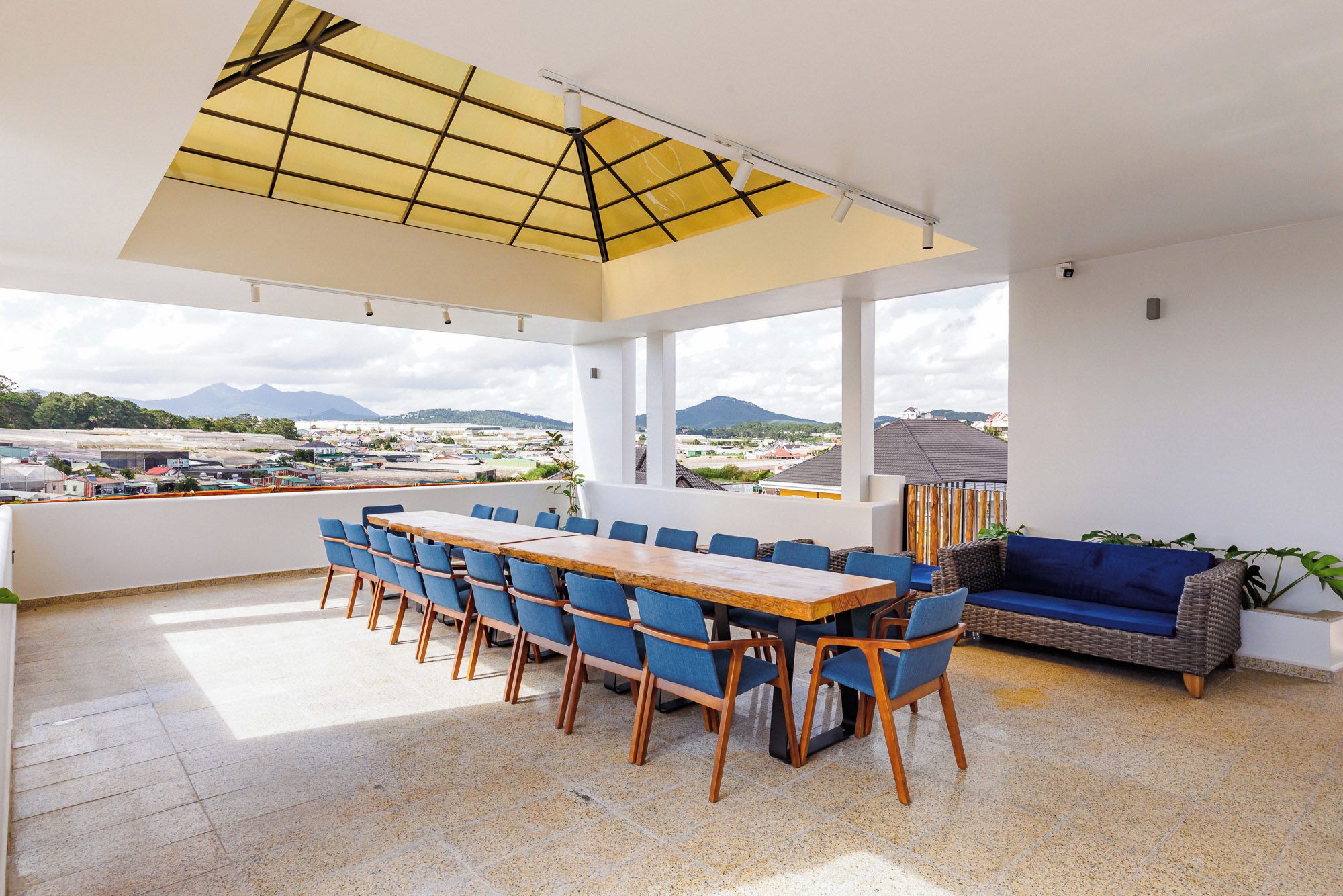 A modern outdoor dining area with a view of a cityscape and mountains.