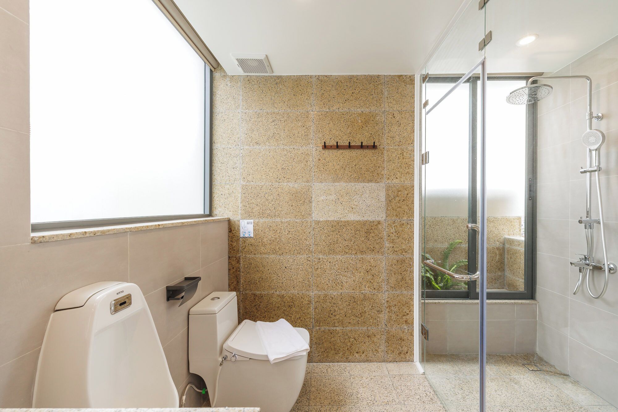 Ein modernes Badezimmer mit Toilette, Dusche und Fenster.