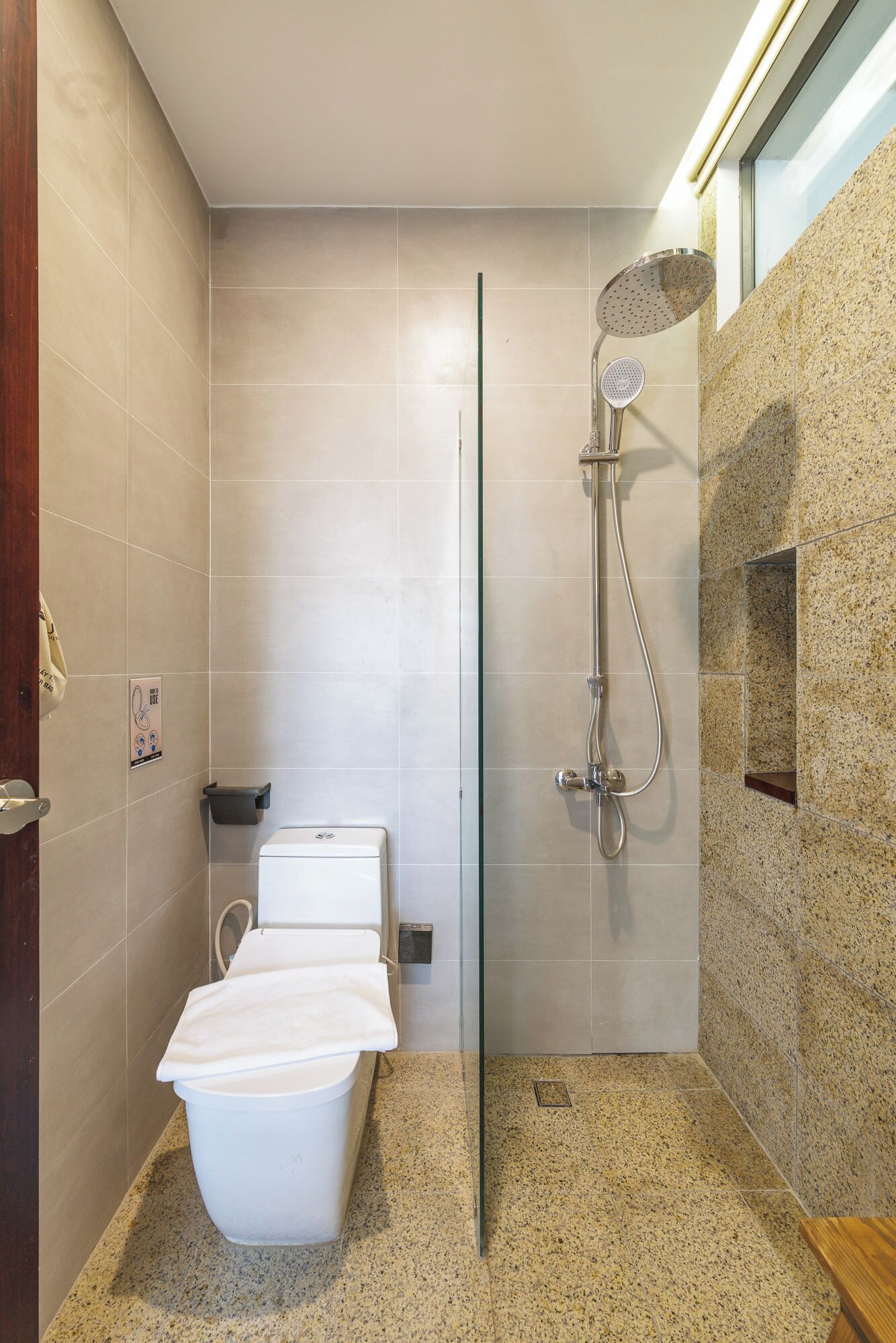 A modern bathroom with a glass-enclosed shower, a toilet, and a bidet.