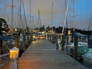 A wooden pier leading to a marina with multiple boats docked.