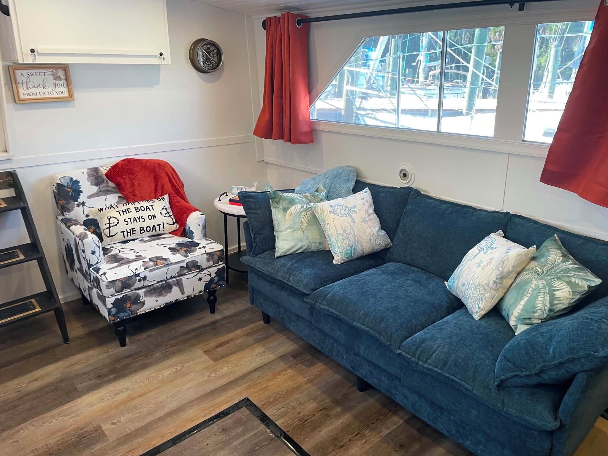 A cozy living room with a blue sofa, a floral armchair, and a small side table.