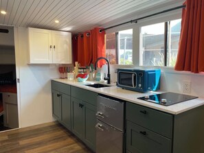 A compact kitchen with a microwave, sink, and cabinets.