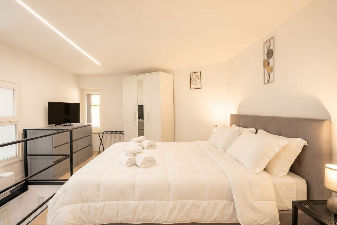 Un dormitorio con cama, televisión, escritorio y armario.