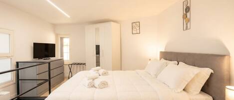 Un dormitorio con cama, televisión, escritorio y armario.