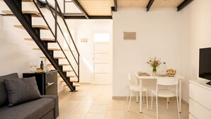 A modern living room with a staircase, a dining area with a table and chairs, and a sofa. - ALL Casa Di Lu – Chic 2-Bedroom Stay for 7 in Bari (Bari)