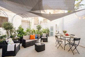 Ein Terrassenbereich im Freien mit Sitzgelegenheiten, einem Esstisch und Blumentöpfen.
