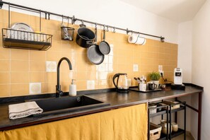 A kitchen with a black sink, a coffee maker, and a shelf with dishes. - ALL Casa Di Lu – Chic 2-Bedroom Stay for 7 in Bari (Bari)