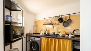 A compact kitchen with a washing machine, a sink with a dish rack, and a coffee maker. - ALL Casa Di Lu – Chic 2-Bedroom Stay for 7 in Bari (Bari)