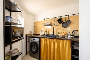Eine kompakte Küche mit Waschmaschine, Spüle mit Geschirrablage und Kaffeemaschine.