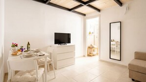 A modern, well-lit room with a dining table set for two, a flat-screen TV, and a large mirror on the wall. - ALL Casa Di Lu – Chic 2-Bedroom Stay for 7 in Bari (Bari)