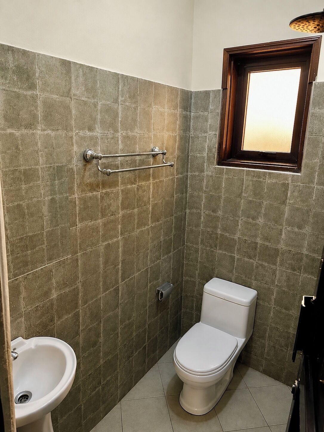 A small bathroom with a toilet, bidet, and a window.