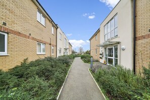A pathway between two brick buildings with a clear sky. - Heathrow Living 2BDR 2BA Apt 09-360stays (Stanwell)