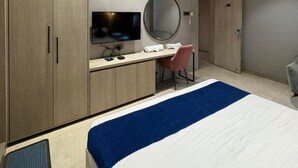 Une chambre à coucher comprenant un lit, un bureau, une chaise, un téléviseur et une armoire.