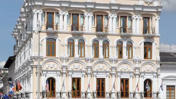 Un edificio histórico con varios balcones, ventanas amplias y banderas.