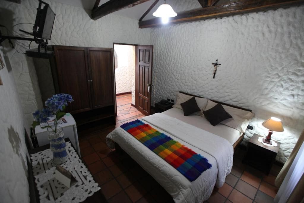 Ein Schlafzimmer mit einem Bett, einem Nachttisch, einer Lampe und einer Tür zu einem anderen Raum.