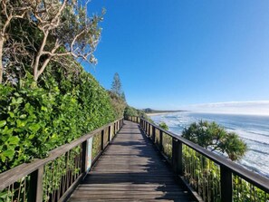 A wooden boardwalk leading to a beach with ocean views. - Poolside 2-bed House in Coolum Beach (Sunshine Coast)
