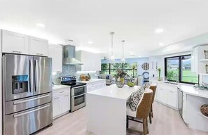 A modern kitchen with stainless steel appliances, a central island, and a view of the outdoors. - RARE FIND! New Renovated Home on Golf Course! (Naples)