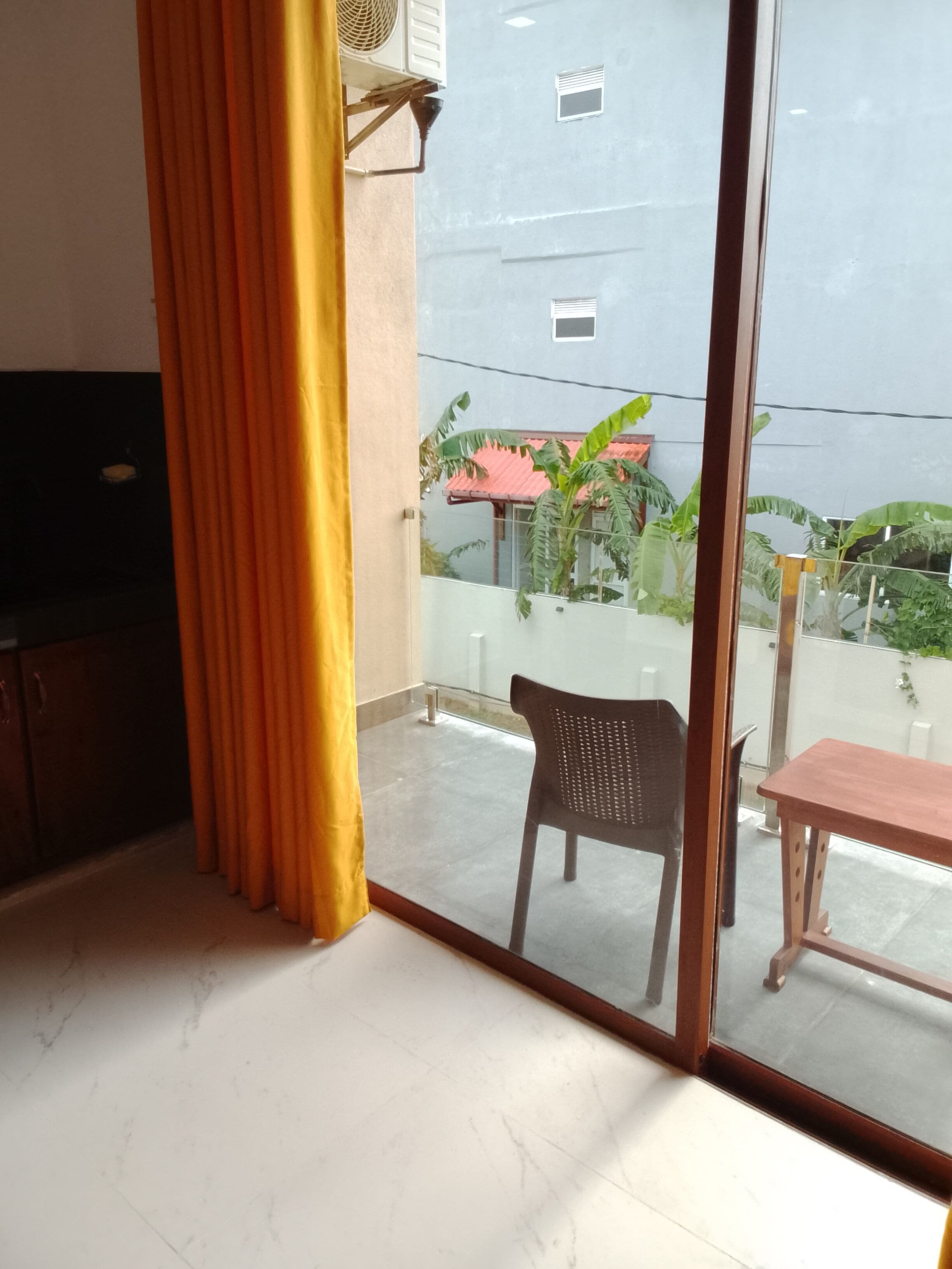 Ein Zimmer mit einer Schiebetür aus Glas, die zu einem Außenbereich mit Stuhl und Tisch führt.
