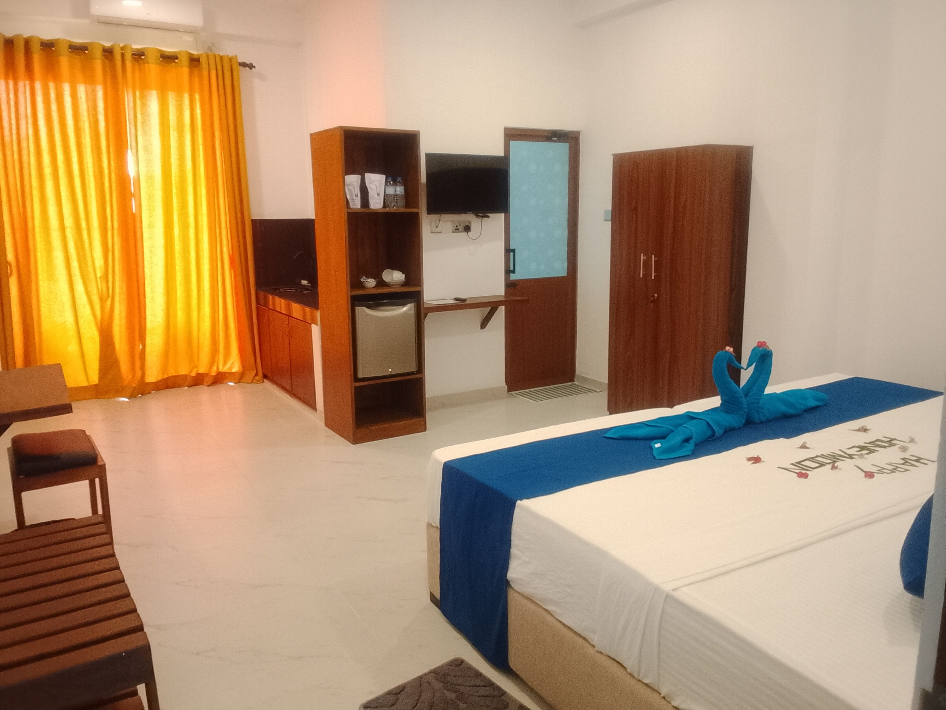 A hotel room with a bed, a desk, a wardrobe, and a television.