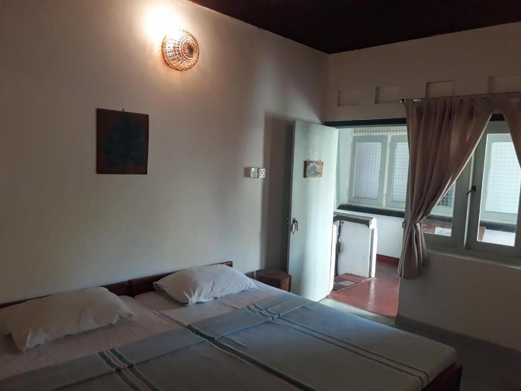 Una habitación con una cama, un escritorio, una silla y un ventanal con cortinas.