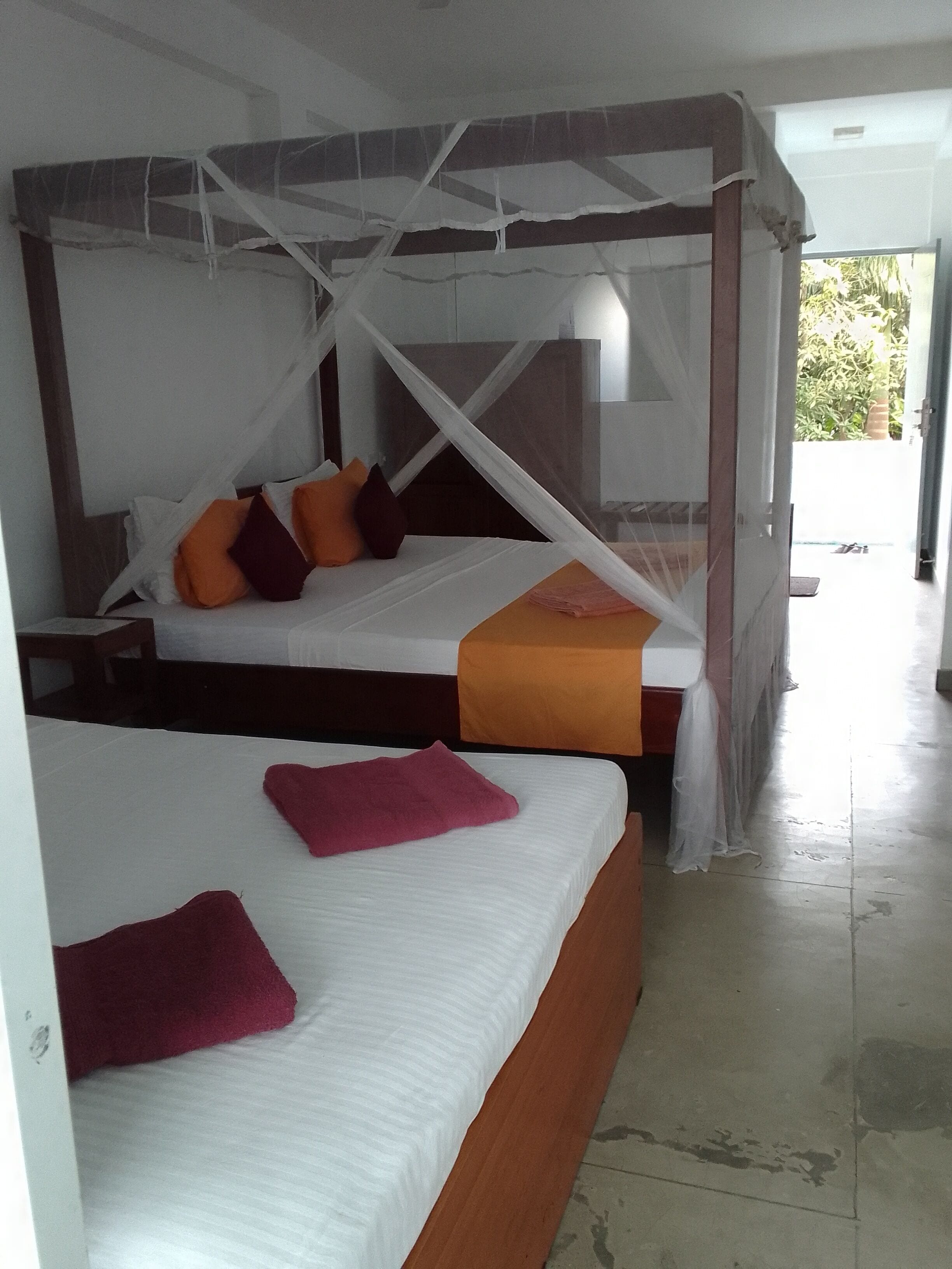Una habitación con dos camas, cada una con dosel. Las camas tienen almohadas y una colcha.