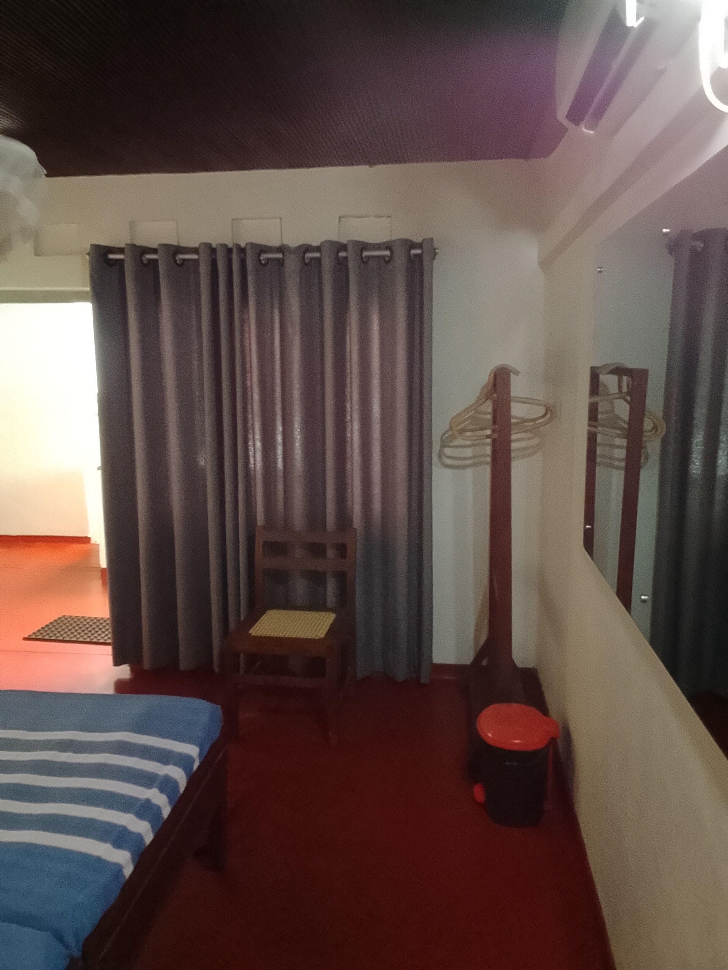 A room with a bed, a chair, a small table, and a mirror on the wall.
