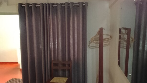 A room with a bed, a chair, a small table, and a mirror on the wall.