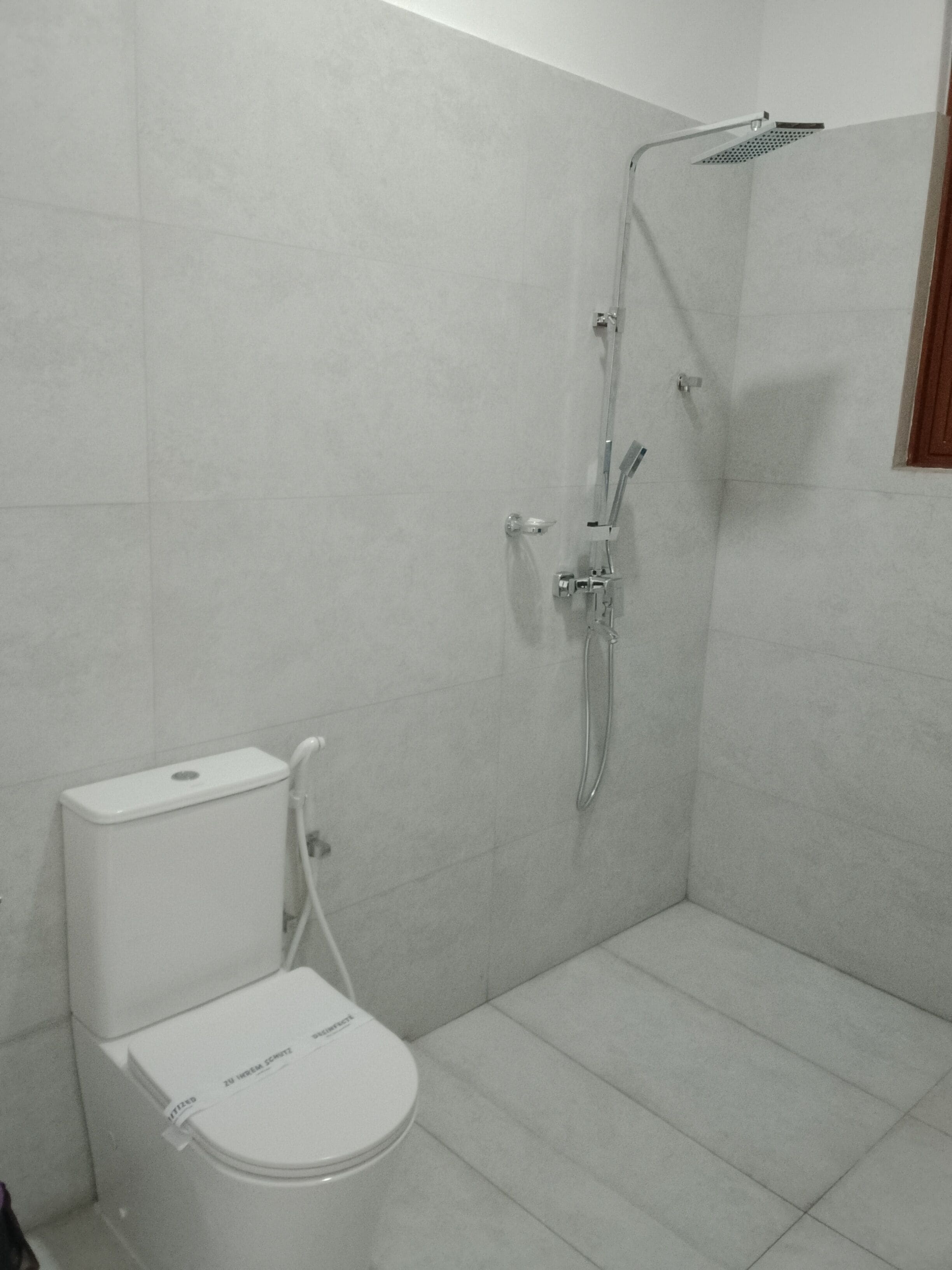 Un baño con inodoro, ducha y paredes con azulejos.